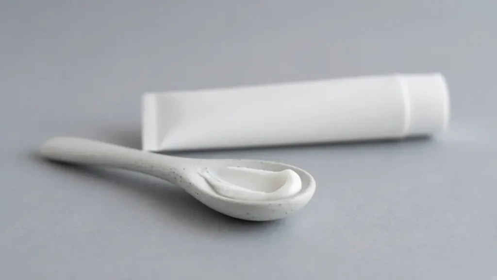 A tube of skin care cream beside a folded cloth